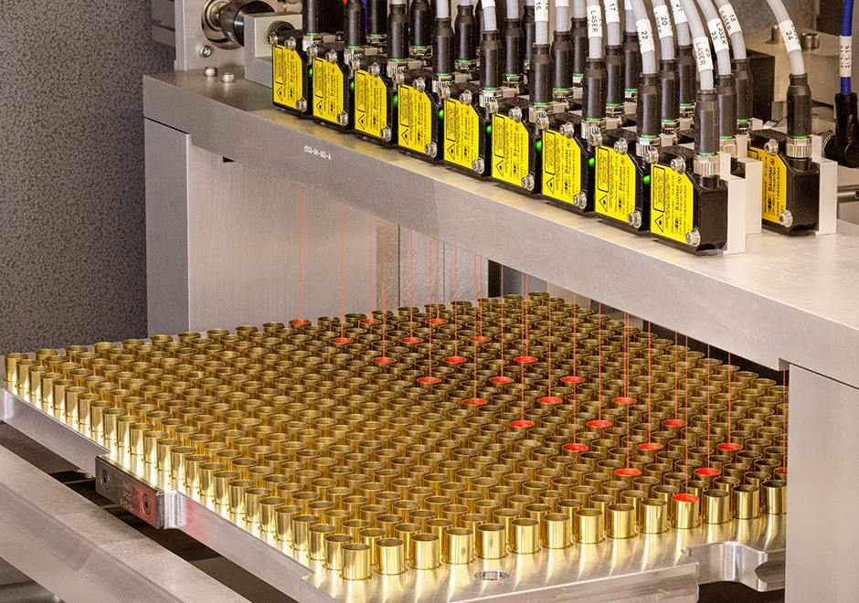 A bank of lasers light up cartridges being manufactured with red.