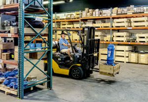 Warehouse with man driving a fork lift with large pump.