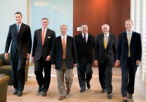 Six executives in paneled office building walking toward camera
